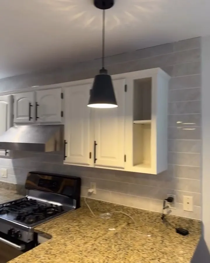 White kitchen cabinets with subway tile backsplash and pendant light