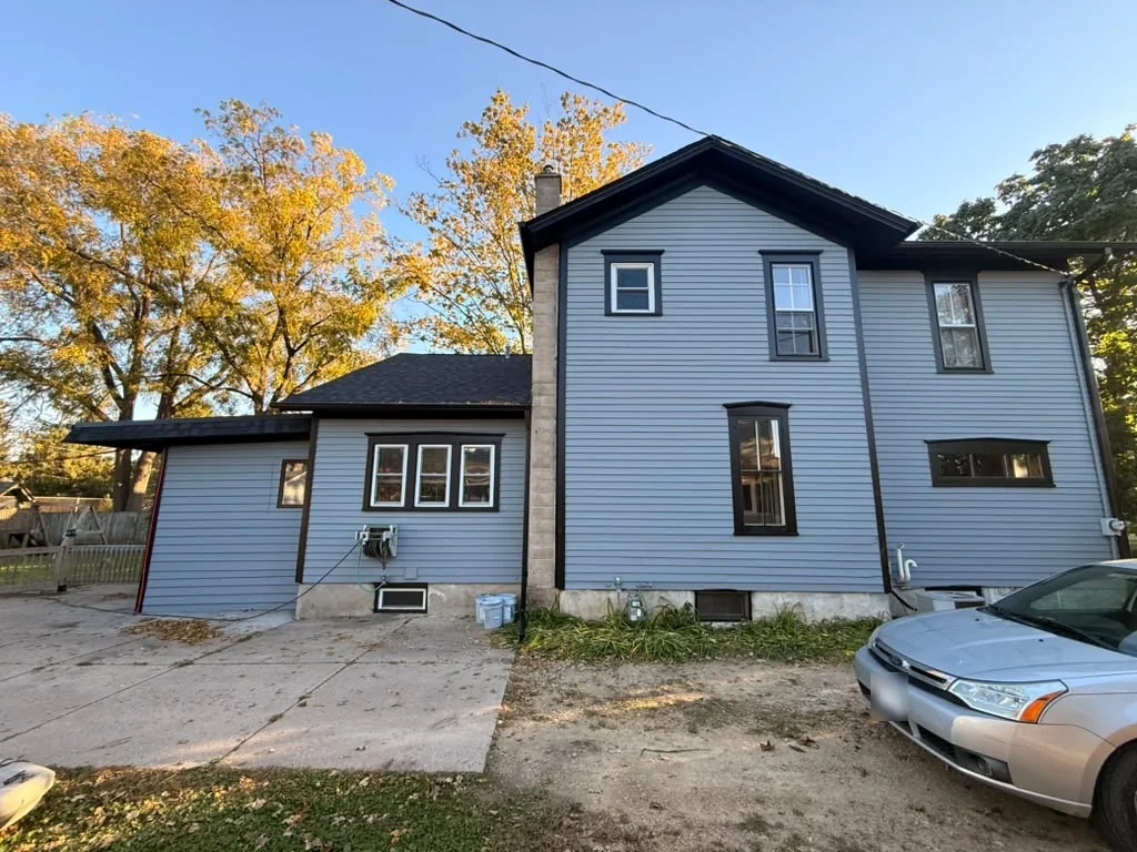 Rear and side of a house with blue-gray siding and dark window trim