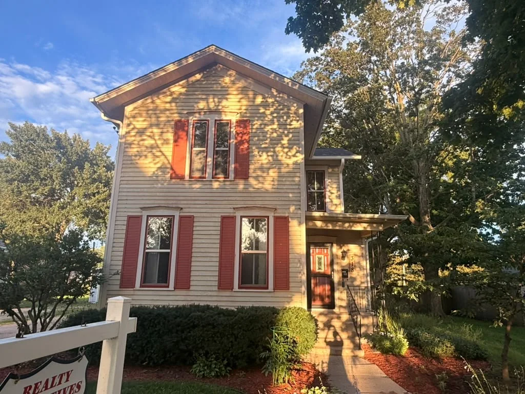The same house before painting: tan siding with red shutters